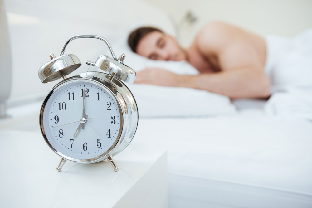 graphicstock-man-sleeping-on-bed-focus-on-clock-which-on-nightstand-near-the-bed_rds3B682e