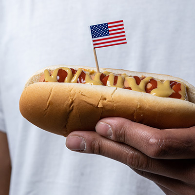 man holding a hot dog with an american flag pick stuck in it