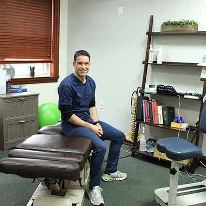 Dr Gulotta sitting on chiropractic table