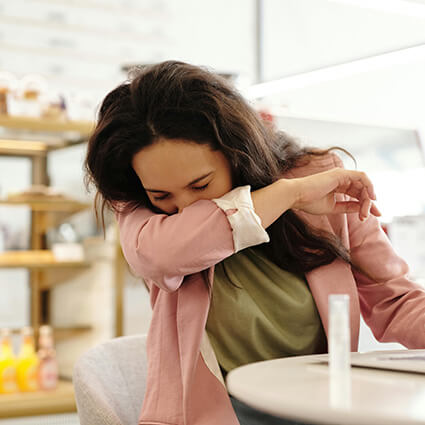 person sneezing into elbow