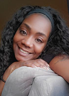 Donique, massage therapist at Go Health Chiropractic, sitting on a gray couch in Robbinsdale, MN
