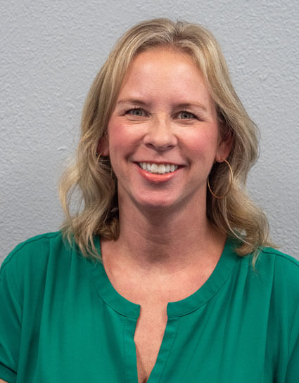 Dr. Lindsay Daniels wearing a green shirt in front of a white wall at Go Health Chiropractic in Robbinsdale, MN