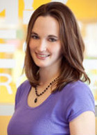 Angie, office manager/financial specialist wearing a purple shirt in front of a yellow and white background in Robbinsdale, MN