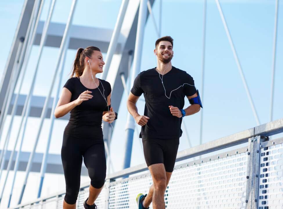 Male and female running on a bridge