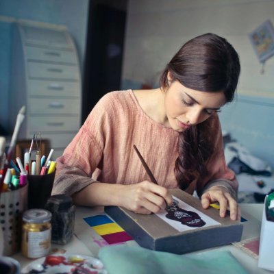 Female artist deeply engaged in painting at her creative studio workspace.