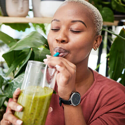 woman drinking green smoothie from straw