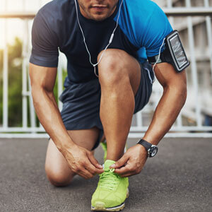 man lacing up his running shoes