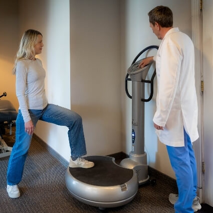 Schultz Chiropractic & Acupuncture patient stepping on vibration machine