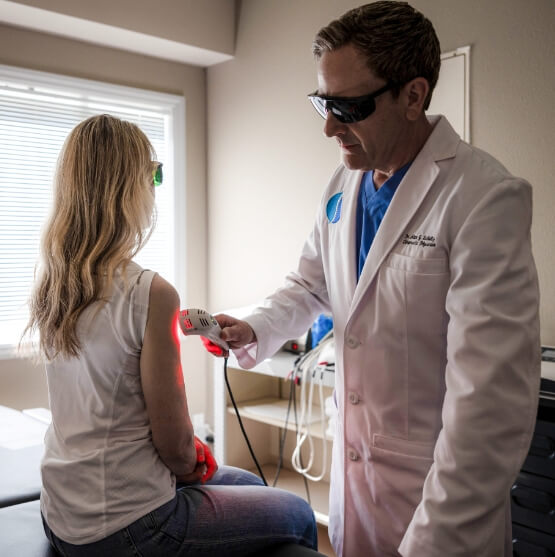 Johnston chiropractor Dr Alan using laser tool on patients arm
