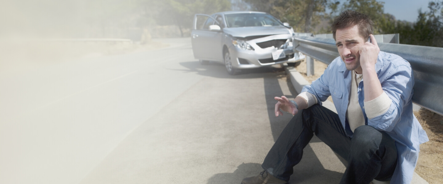 Man sitting at the side of the road after car accident
