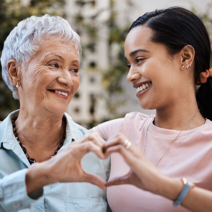 Elderly lady and young female making heart with hands