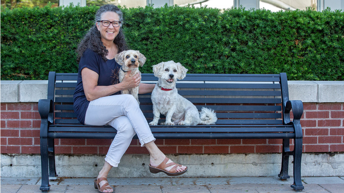 Dr Katharine on bench with her dogs sitting on bench