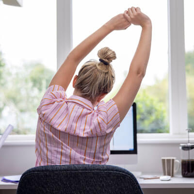 woman stretching arms at desk