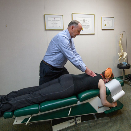 Dr. David Egan adjusting patient's upper back.