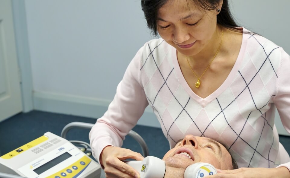 Chiropractor using tool on patient's neck