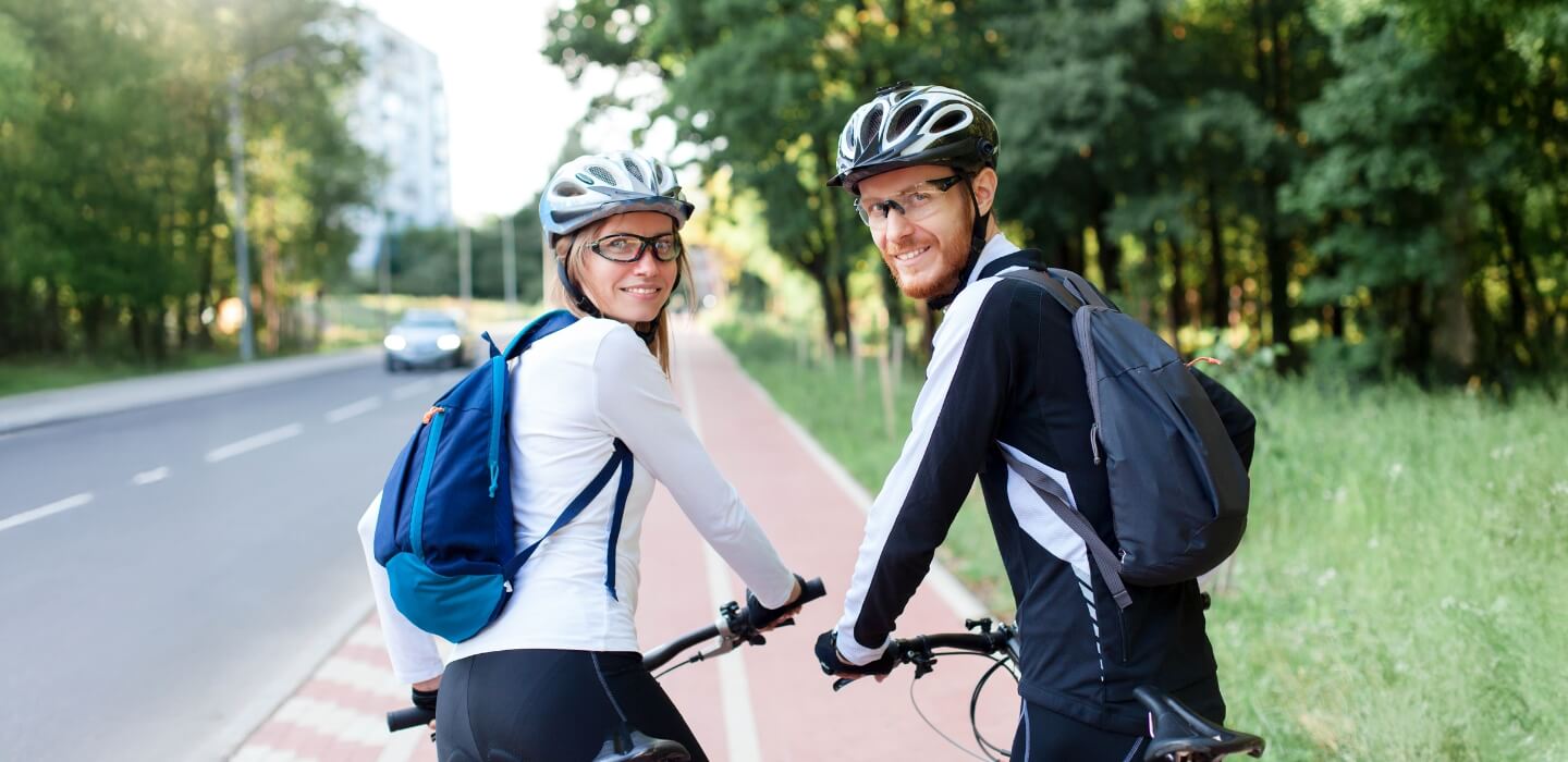 two people riding bicycles and smiling at the camera