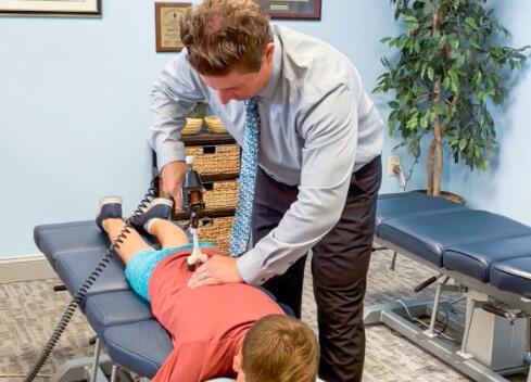 Feasterville chiropractor using a tool to adjust a patient's back