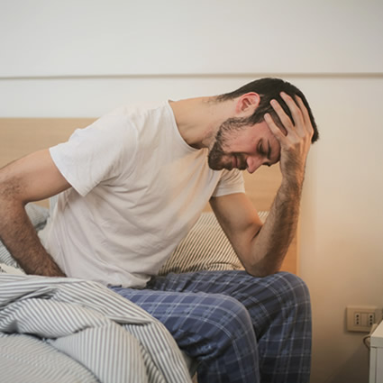 man with pain sitting on bed