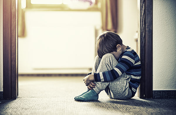 Depressed little boy sitting on the floor