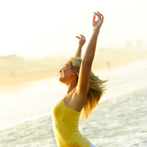 Lady on beach with hands in air