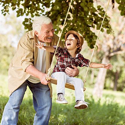 Older man pushing child on swing