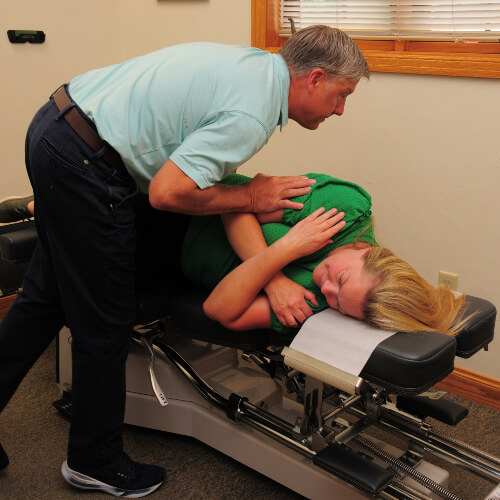 Chiropractor adjusting a patient wearing green shirt