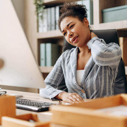 woman in grey blazer with neck pain at desk 