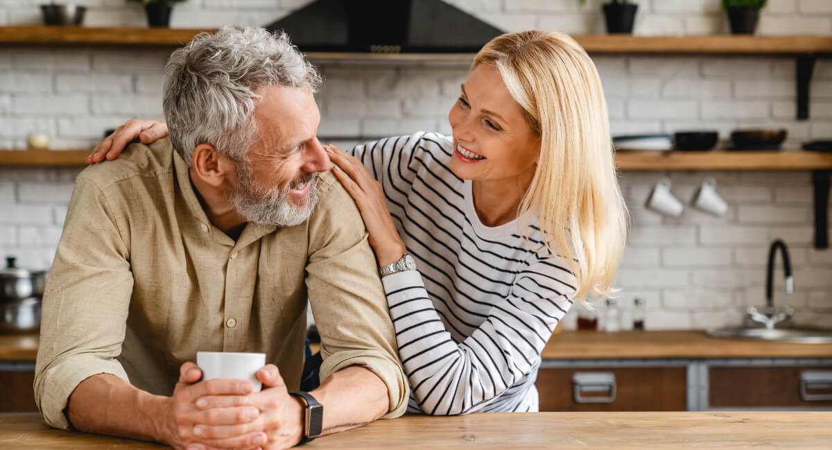 Smiling man and woman sitting in kitchen
