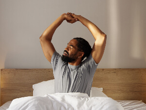 man sitting in bed and stretching arms upward