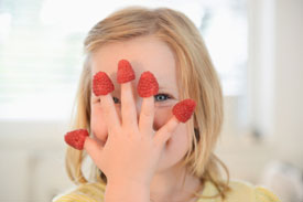 Young girl with five raspberries on her fingers