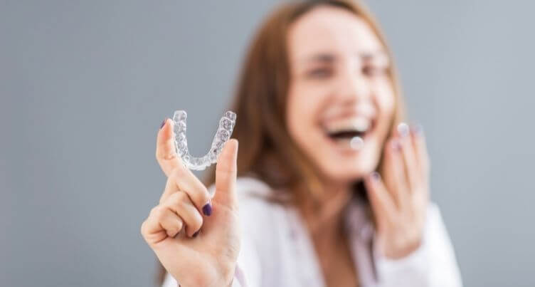 Woman holding a clear aligner.