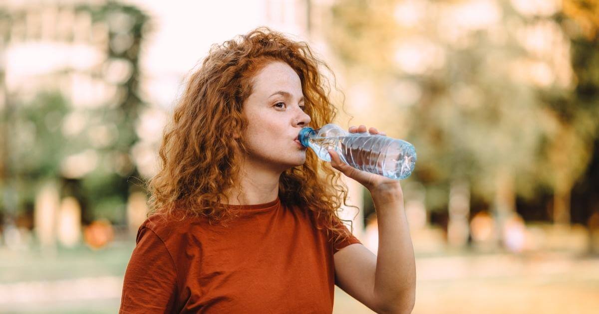 Woman sipping water bottle.