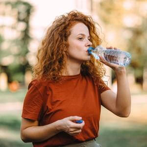 Woman sipping water bottle.