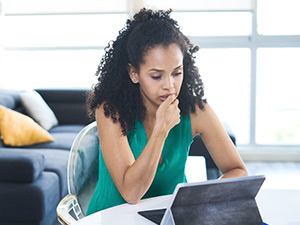 woman chewing on her nails sitting at her computer