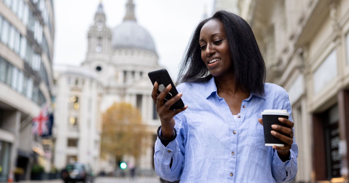 Busy woman walking holding phone and coffee.