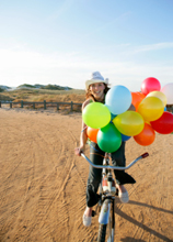 Woman riding a bike with balloons