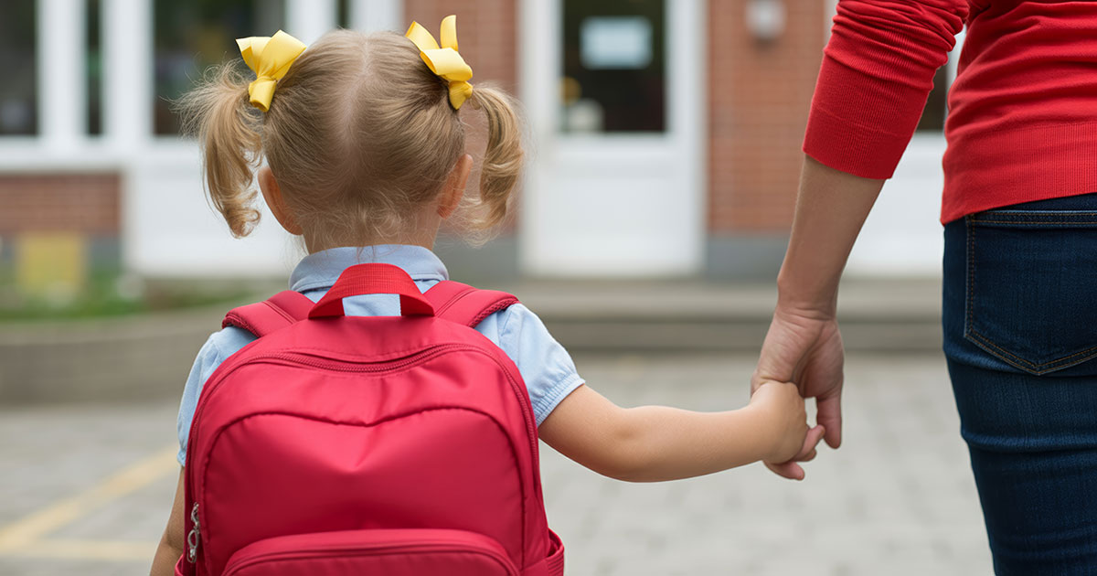 Child wearing backpack holding hand
