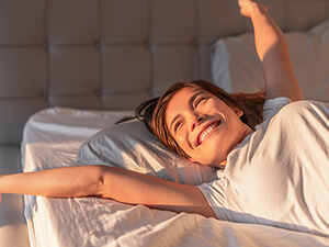 woman in bed waking up smiling
