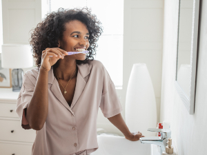 woman brushing teeth in front of mirror