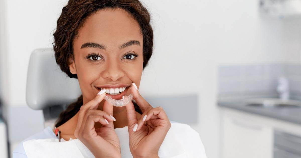 Woman smiling with teeth whitening tray.