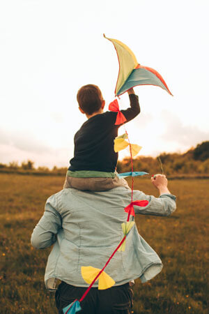 dad holding a boy flying a kite