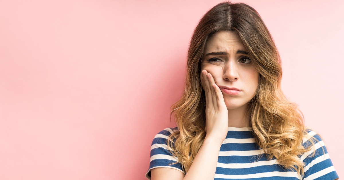 Woman holding the side of her face in pain.