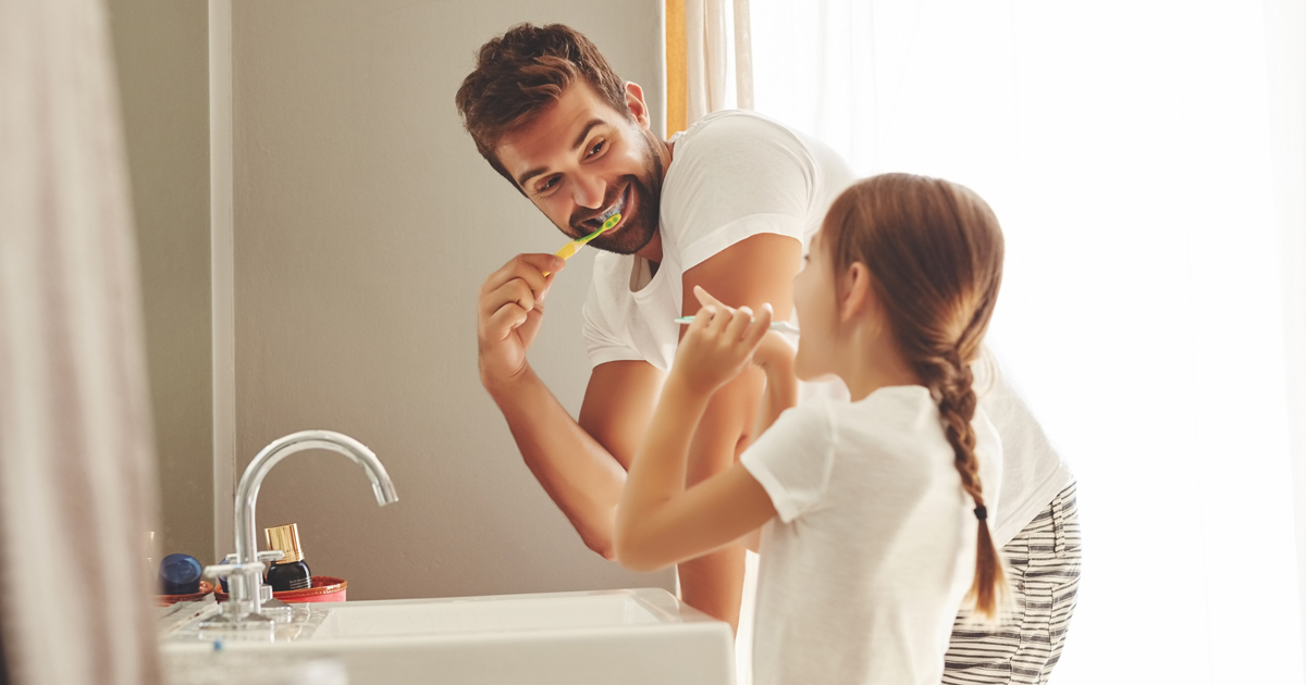 Father and daughter brushing teeth