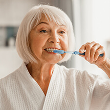 woman in a robe brushing her teeth