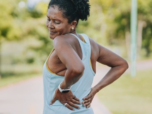 woman outdoors with hands on lower back