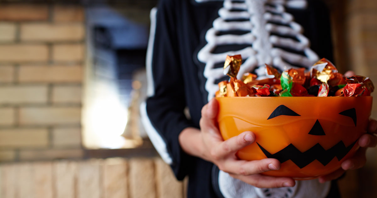 Child holding bucket of Halloween candy