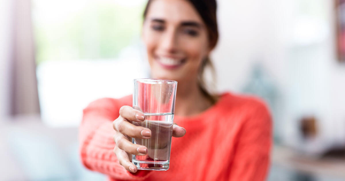 woman holding out a glass of water