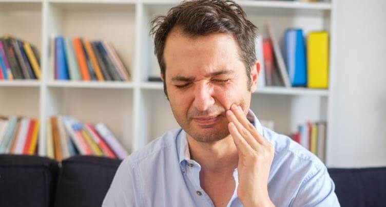 Man holding cheek in pain.