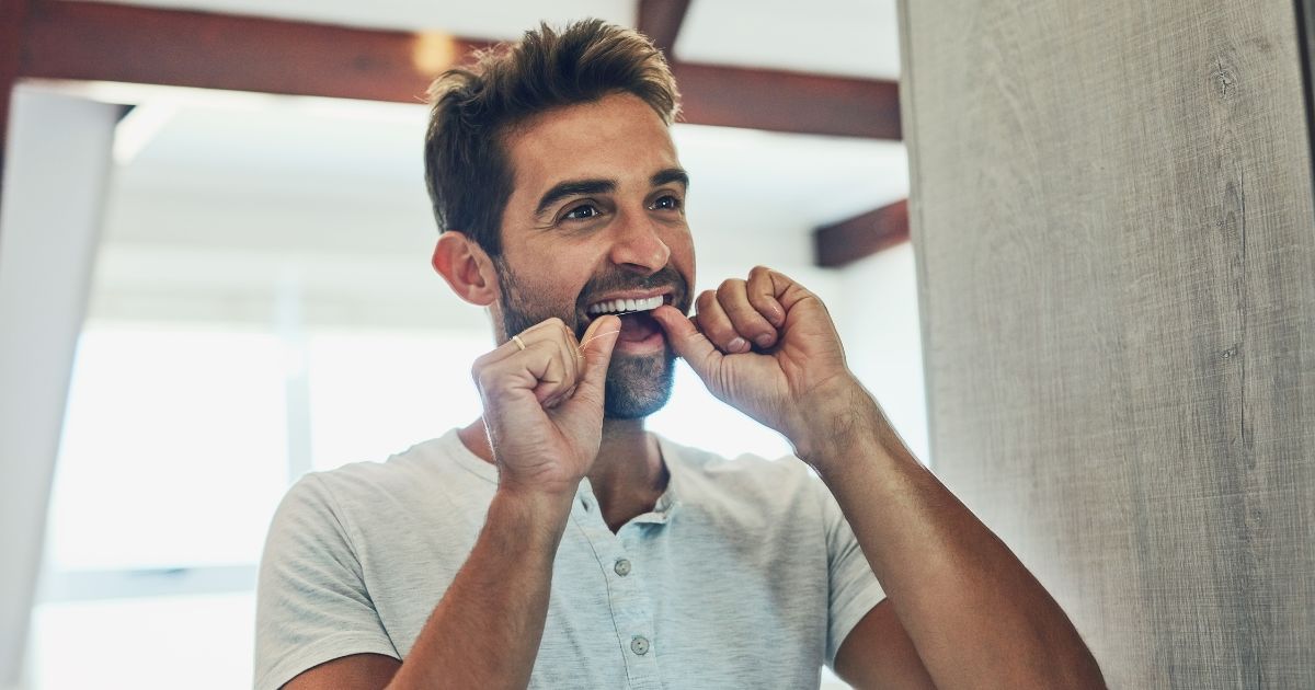 Man flossing in mirror.