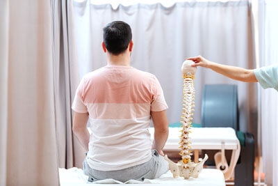 man sitting next to spine model